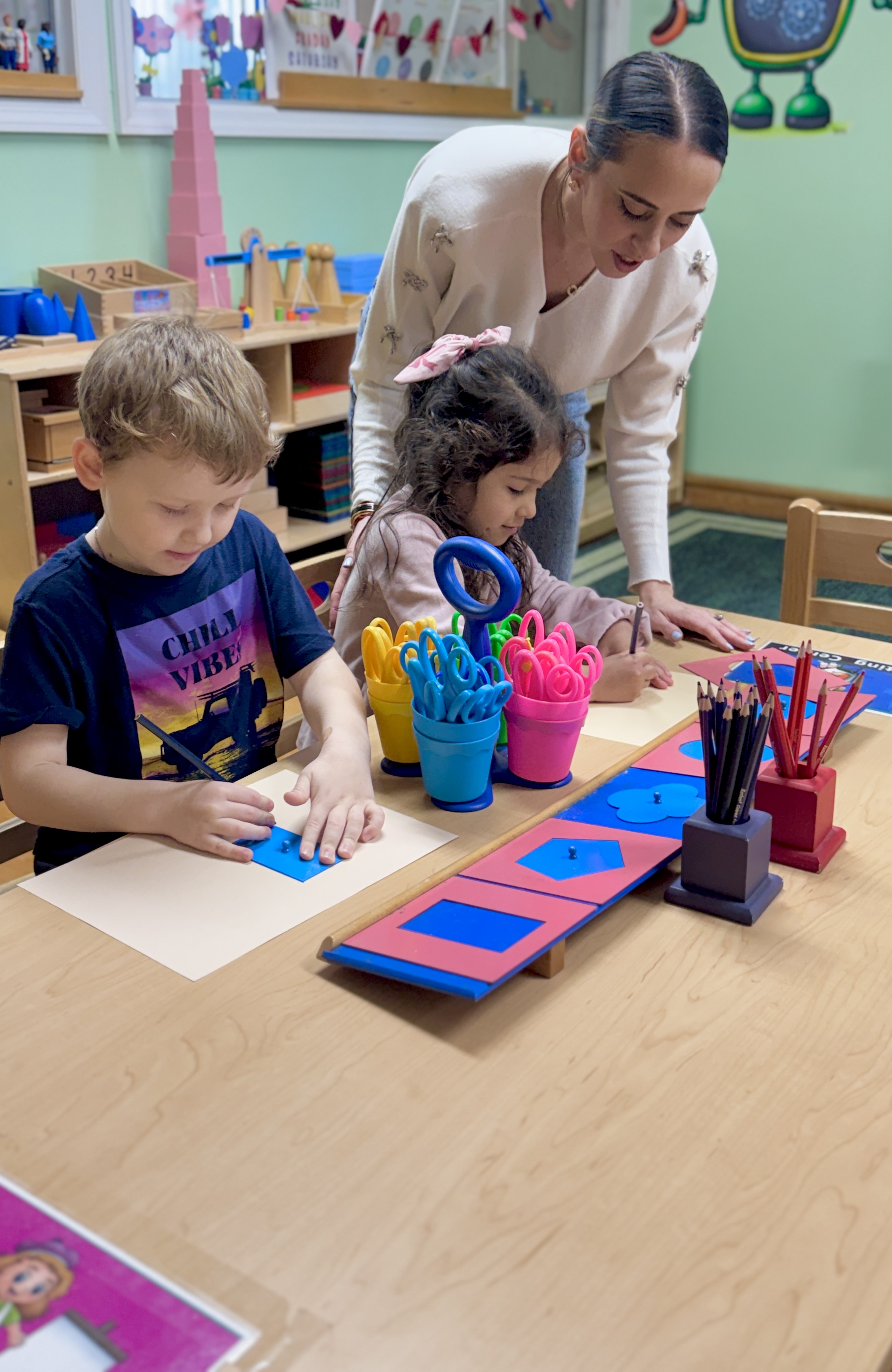 Teacher helping children trace shapes