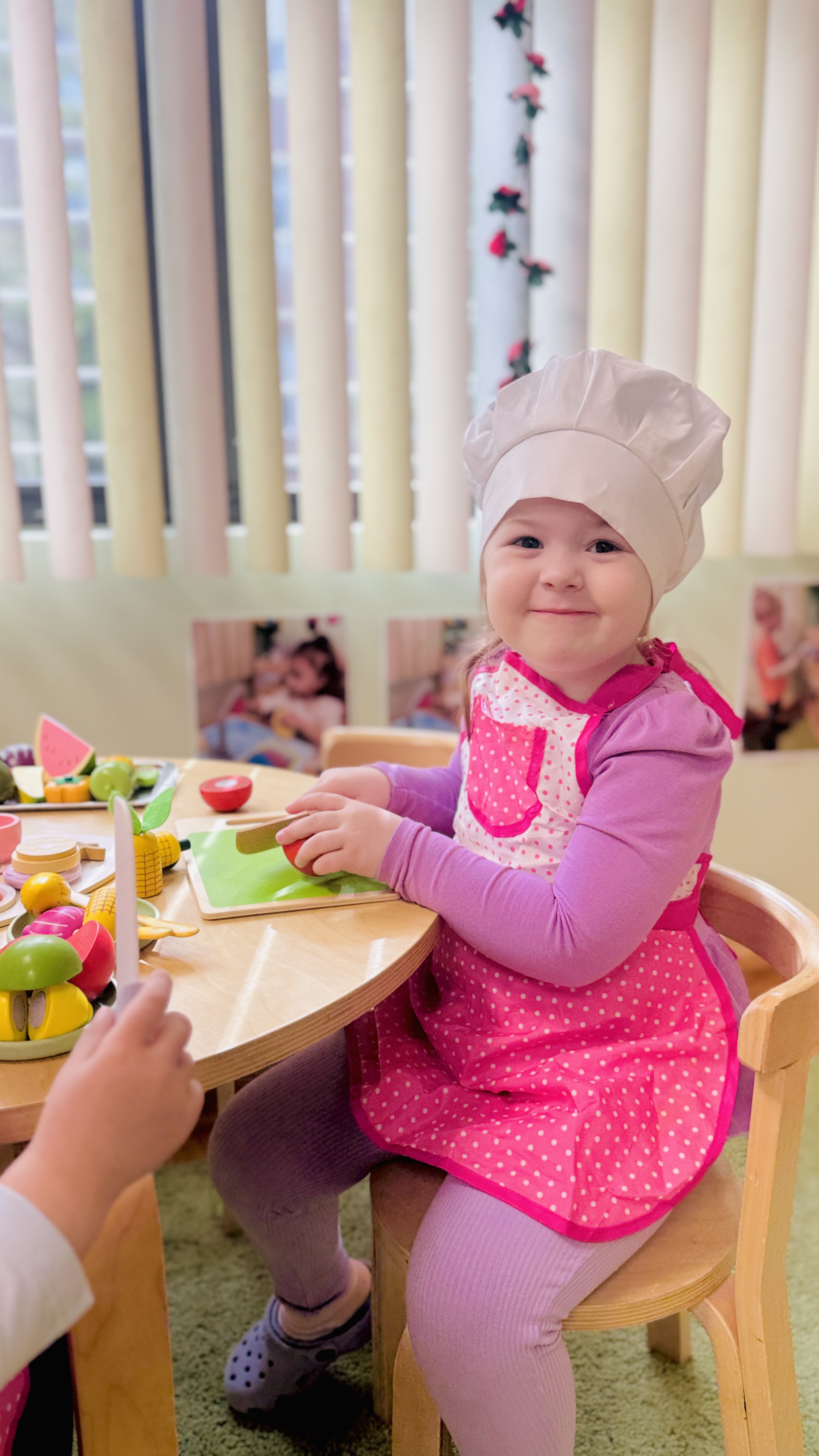 Toddler in chef hat smiling during cooking class